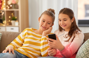 Image showing happy girls with smartphone and earphones at home