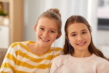 Image showing happy girls with earphones listen to music at home