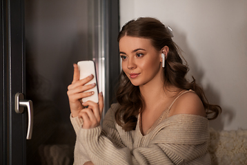 Image showing woman with smartphone and earphones at home