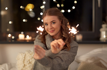 Image showing happy young woman with sparklers in bed at home