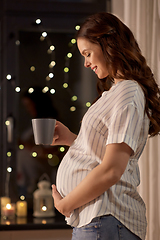 Image showing happy pregnant woman drinking tea at home