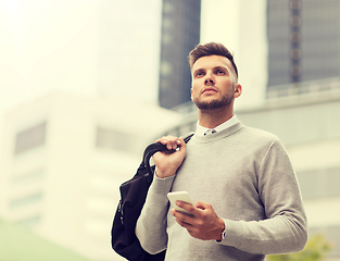 Image showing young man with smartphone and bag in city