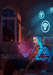 Image showing Man using gadget and receive neon notifications at home at night