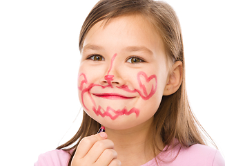 Image showing Little girl is applying lipstick on her cheek