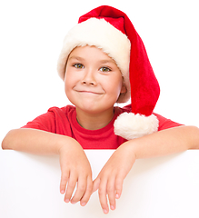 Image showing Little girl in santa hat is holding blank board