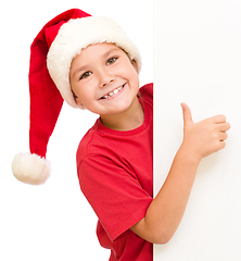 Image showing Little girl in santa hat is holding blank board