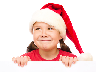 Image showing Little girl in santa hat is holding blank board