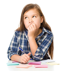 Image showing Girl is writing on color stickers using pen