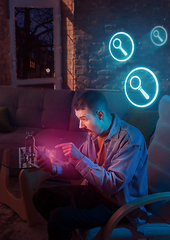 Image showing Man using gadget and receive neon notifications at home at night