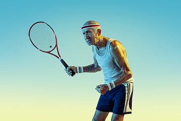 Image showing Senior man playing tennis in sportwear on gradient background and neon light