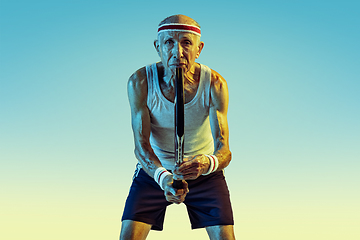 Image showing Senior man playing tennis in sportwear on gradient background and neon light