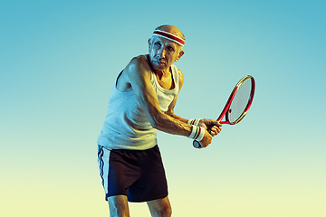 Image showing Senior man playing tennis in sportwear on gradient background and neon light