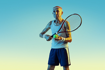 Image showing Senior man playing tennis in sportwear on gradient background and neon light