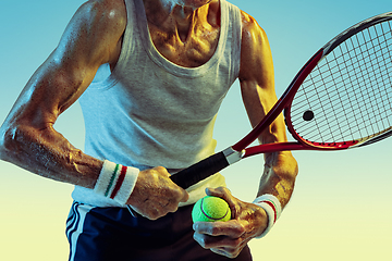 Image showing Senior man playing tennis in sportwear on gradient background and neon light