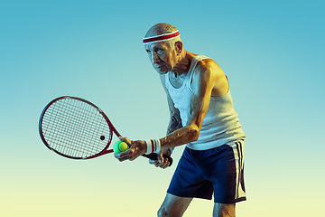 Image showing Senior man playing tennis in sportwear on gradient background and neon light