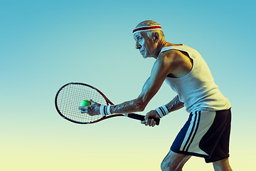 Image showing Senior man playing tennis in sportwear on gradient background and neon light