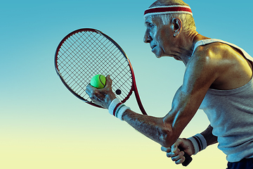 Image showing Senior man playing tennis in sportwear on gradient background and neon light