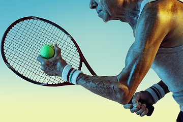 Image showing Senior man playing tennis in sportwear on gradient background and neon light