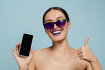 Image showing Portrait of beautiful young woman with bright make-up isolated on blue studio background