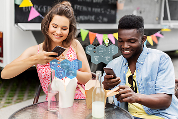Image showing couple with smartphones eating wok at food truck