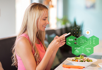 Image showing happy woman with smartphone eating at restaurant