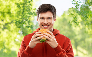 Image showing happy young man eating hamburger