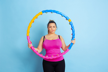 Image showing Young caucasian plus size female model\'s training on blue background