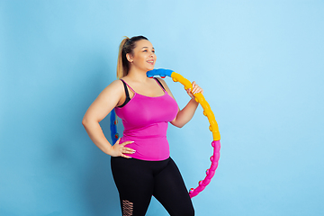 Image showing Young caucasian plus size female model\'s training on blue background