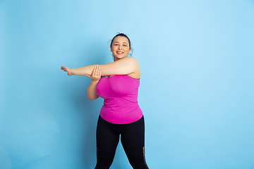 Image showing Young caucasian plus size female model\'s training on blue background