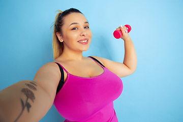 Image showing Young caucasian plus size female model\'s training on blue background