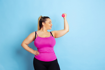 Image showing Young caucasian plus size female model\'s training on blue background