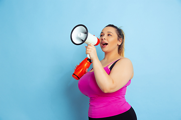 Image showing Young caucasian plus size female model\'s training on blue background