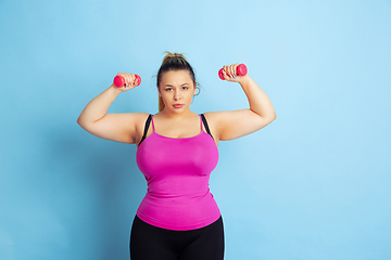 Image showing Young caucasian plus size female model\'s training on blue background