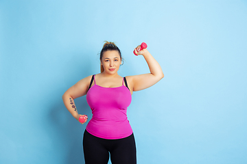 Image showing Young caucasian plus size female model\'s training on blue background