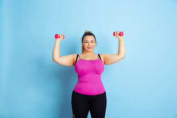 Image showing Young caucasian plus size female model\'s training on blue background