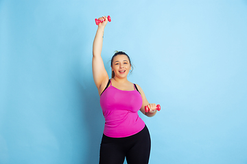 Image showing Young caucasian plus size female model\'s training on blue background