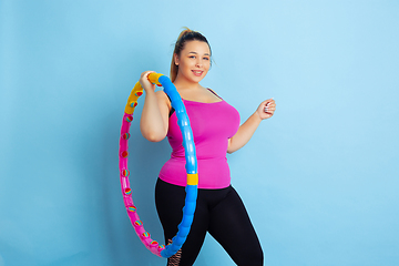 Image showing Young caucasian plus size female model\'s training on blue background