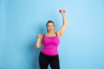 Image showing Young caucasian plus size female model\'s training on blue background