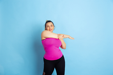 Image showing Young caucasian plus size female model\'s training on blue background