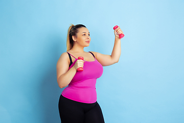 Image showing Young caucasian plus size female model\'s training on blue background