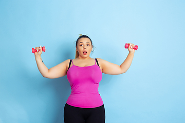 Image showing Young caucasian plus size female model\'s training on blue background