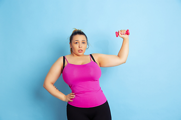 Image showing Young caucasian plus size female model\'s training on blue background