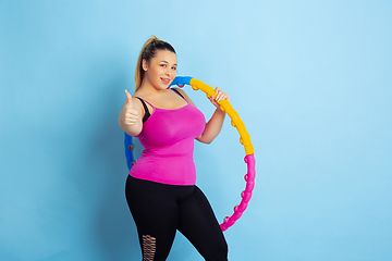 Image showing Young caucasian plus size female model\'s training on blue background