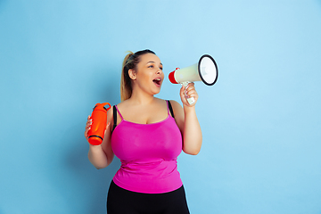 Image showing Young caucasian plus size female model\'s training on blue background