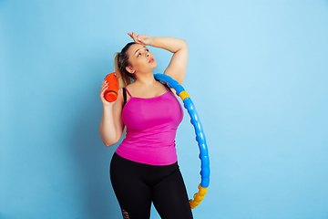 Image showing Young caucasian plus size female model\'s training on blue background