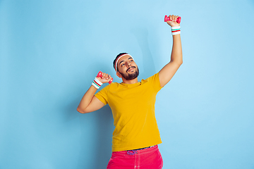 Image showing Young caucasian man in bright clothes training on blue background