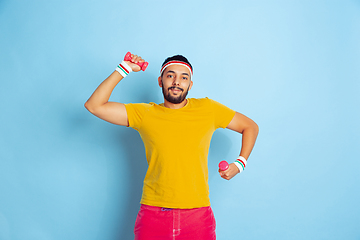 Image showing Young caucasian man in bright clothes training on blue background