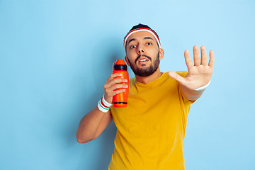 Image showing Young caucasian man in bright clothes training on blue background