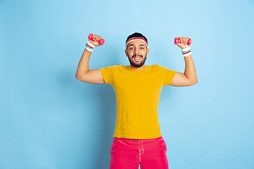 Image showing Young caucasian man in bright clothes training on blue background