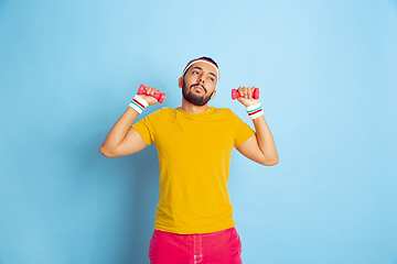 Image showing Young caucasian man in bright clothes training on blue background